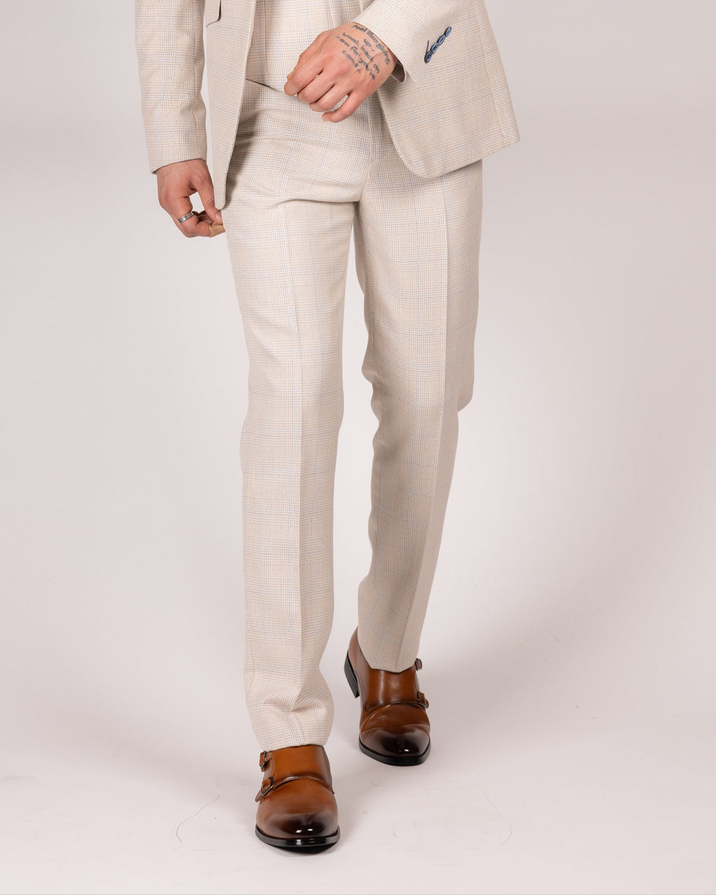 A male model wearing caridi beige slim fit trousers with a matching jacket and tie, standing against a plain background.