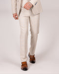 A male model wearing caridi beige slim fit trousers with a matching jacket and tie, standing against a plain background.