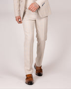 A male model wearing caridi beige slim fit trousers with a matching jacket and tie, standing against a plain background.