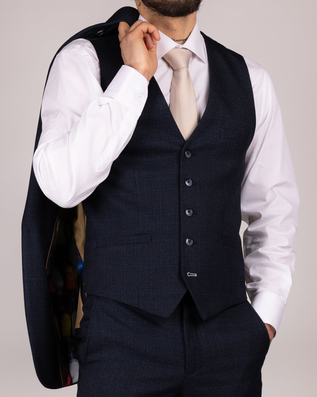A person wearing a caridi navy slim fit waistcoat with a white shirt and a tie.