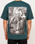 Back view of a men’s oversized green T-shirt with a large monochrome photo-print featuring blurred faces.