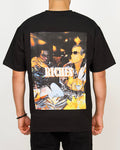 Back view of a men’s oversized black T-shirt featuring a colourful nightlife photo-print with “RICHES” branding.