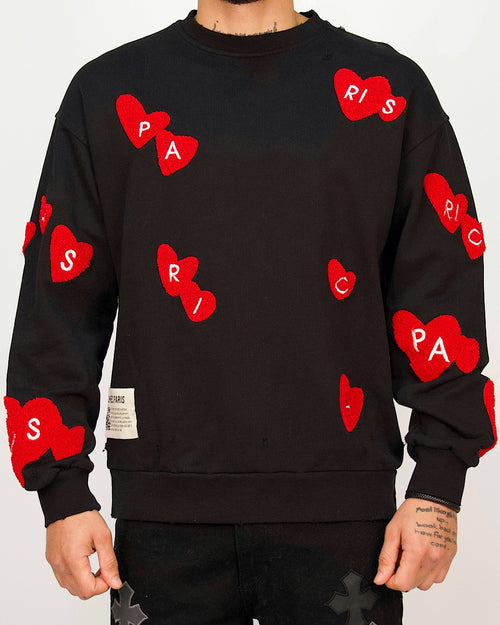 Front view of a men’s regular-fit black sweatshirt featuring raised red chenille heart patches spelling out Paris.