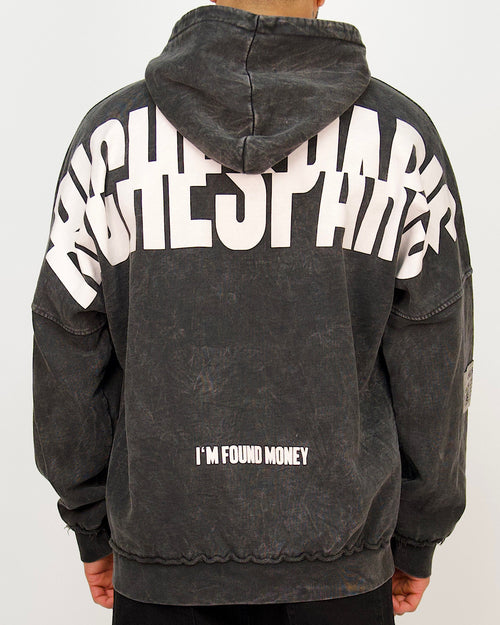 Back view of a men’s oversized washed black hoodie featuring a large Riches Paris back print and “I’M FOUND MONEY” text.