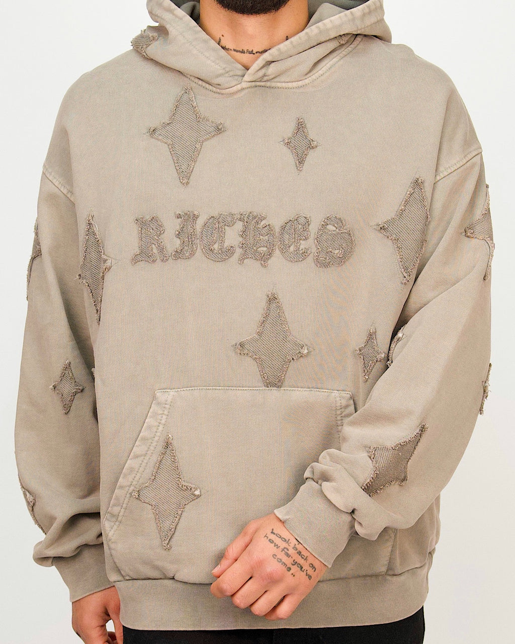 Front view of a men’s oversized smoked hoodie featuring distressed star patches and a textured RICHES chest detail.