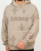 Front view of a men’s oversized smoked hoodie featuring distressed star patches and a textured RICHES chest detail.