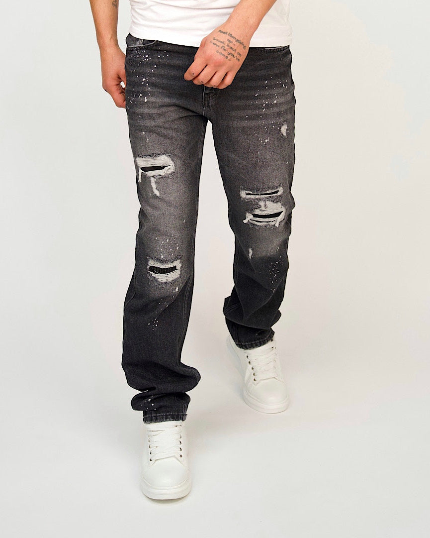 Men’s relaxed-leg black jeans with heavy distressing and paint-splatter detailing.